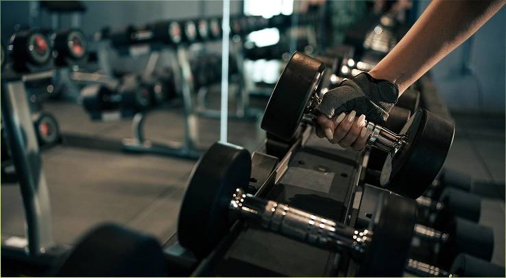 Close-up van een vrouwenhand die een halter optilt in de sportschool