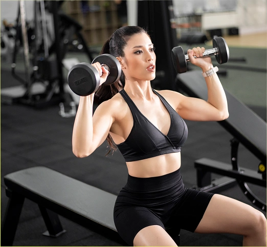 Een meisje doet een schouderoefening met halters terwijl ze op een bankje zit