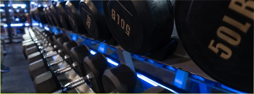 Een reeks halters op een rek in een moderne fitnessruimte met verlichting